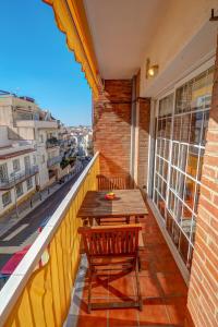 balcón con mesa de madera y 2 sillas en The Beach Apartment by Hello Homes Sitges, en Sitges