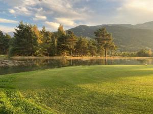 a golf course with a lake and mountains in the background at Petit chalet 40 m2 en Ubaye BARCELONNETTE in Barcelonnette