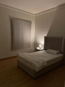 a bedroom with a bed and a window with a lamp at Family Furnished Apartment in Khobar in Al Khobar