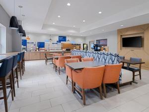 a restaurant with tables and chairs and a tv at Holiday Inn Express & Suites Lakeland North I-4, an IHG Hotel in Lakeland