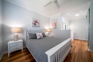 a white bedroom with a bed and two lamps at Azure on Anderson Family home in Henley Beach South