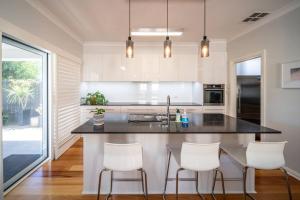 a kitchen with a black counter and white appliances at Azure on Anderson Family home in Henley Beach South