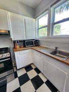 a kitchen with white cabinets and a sink and a microwave at Cozy Vintage Bungalow @Mills50 District in Orlando