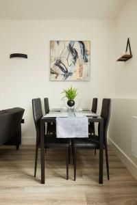 a dining room table with black chairs and a painting at Pottergate Views in Norwich