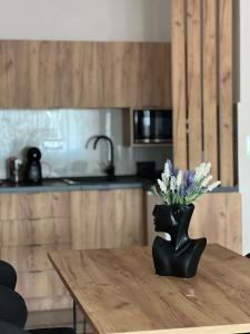 a black vase with flowers on a wooden table at Apartment33 in Strumica