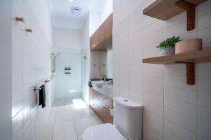 a white bathroom with a toilet and a sink at Wisteria Cottage c1880 in Adelaide