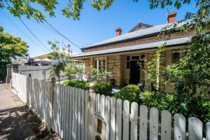 a white picket fence in front of a house at The Oxford Hyde Park 4BR Cottage in Unley