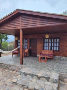 a log cabin with a hammock and a patio at Cabaña Los Abuelos in Coronel Moldes