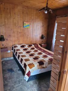 a bedroom with a bed in a wooden wall at Cabaña Los Abuelos in Coronel Moldes