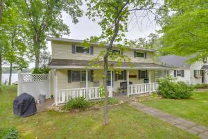 una casa blanca con un porche y un patio en Waterfront Cable Lake Cabin with Grill!, en Woodland Beach