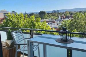 einen Tisch und einen Stuhl auf einem Balkon mit Aussicht in der Unterkunft The East Ender 1BR Balcony City View in Adelaide