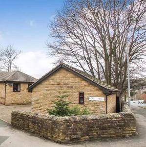 a brick building with a sign on it at Lister Park Bradford Stylish 1bed Coach House - Quiet & Tranquil Cottage & Parking in Shipley