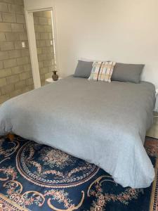 uma cama com um cobertor cinzento em cima de um tapete em The Architects House Villa 1 2BR em Hahndorf