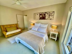 a small bedroom with a bed and a chair at Poolstraat 16 in Agulhas