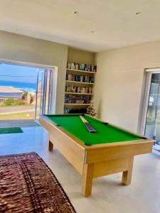 a green pool table in a living room with a book shelf at Poolstraat 16 in Agulhas