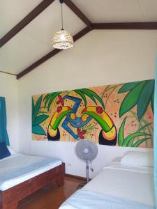 Habitación con 2 camas y una pintura en la pared. en MisMiriam, en Tortuguero