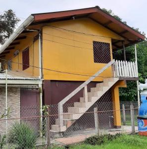 Una casa amarilla con escaleras al costado. en MisMiriam, en Tortuguero
