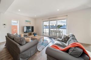 a living room with two couches and a television at Level Up Henley - Modern Comfort near Beach & Dining in Grange