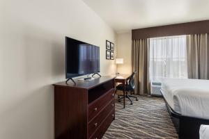 a hotel room with a bed and a flat screen tv at Cobblestone Hotel & Suites - De Pere Green Bay in De Pere