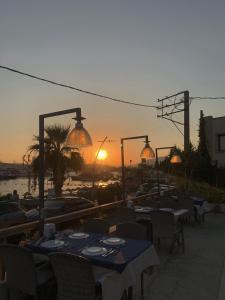 un grupo de mesas y sillas con la puesta de sol en el fondo en Akkan Beach Hotel, en Bodrum City