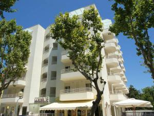 a tall white building with a tree in front of it at Wally Residence in Rimini