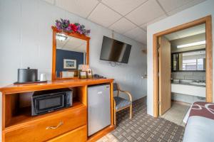 a room with a tv and a cabinet with a microwave at Sleep-ees Inn, Saginaw & Frankenmuth in Saginaw