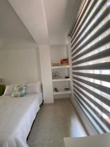 a bedroom with a bed and a window with blinds at APARTAESTUDIO EN SAN FERNANDO in Cali