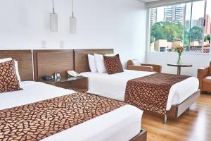 a hotel room with two beds and a window at Hotel Poblado Alejandria in Medellín