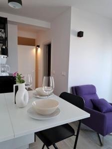 een witte tafel met twee wijnglazen en een paarse bank bij Sea view in Hvar