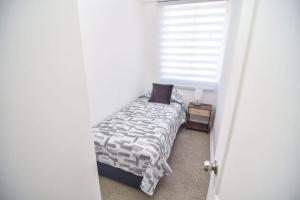 een kleine slaapkamer met een bed en een raam bij Apartamento Altos del boldo, cómodo in Curicó
