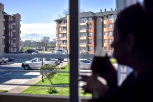 una persona mirando por una ventana en un estacionamiento en Apartamento Altos del boldo, cómodo, en Curicó