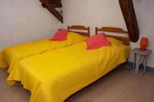 2 camas en una habitación con sábanas amarillas y almohadas rojas en Residence du marche, en Jonzac