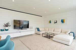 uma sala de estar branca com um sofá branco e uma televisão em Lux Resort Higueron West VXL em Fuengirola