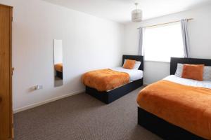 1 dormitorio con 2 camas y espejo en Ideal home with private parking for contractors & groups, en Birmingham