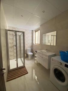a bathroom with a sink and a washing machine at Sunset Seaview Apartments in Marsalforn