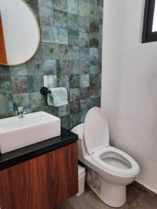 uma casa de banho com um WC, um lavatório e um espelho. em Casa GaTo Tequisquiapan em La Tortuga