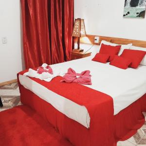 1 dormitorio con 1 cama grande con almohadas y arcos rojos en Hostel Damaris en Puerto Iguazú