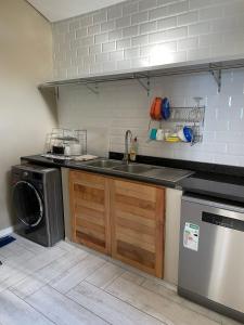 a kitchen with a sink and a washing machine at Umdloti Villa in Umdloti