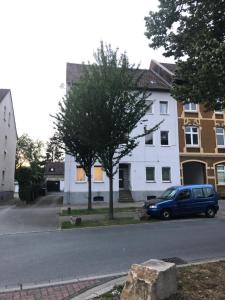赫內的住宿－Seibels SUITES - Wohnung Ruhrgebiet，停在白色建筑前的蓝色汽车