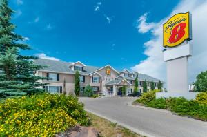 a view of a hotel with a sign and flowers at Super 8 by Wyndham Cochrane in Cochrane