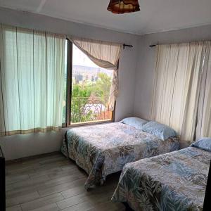 1 dormitorio con 2 camas y ventana grande en Cabaña con terraza y alberca, en San José del Puente