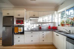 UnleyThat 70s Cottage Parkside Cottage Backyard WiFi的配有白色橱柜和不锈钢冰箱的厨房