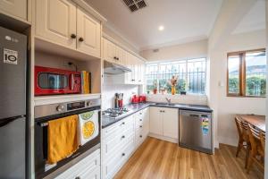 UnleyThat 70s Cottage Parkside Cottage Backyard WiFi的厨房配有白色橱柜和红色微波炉 更多31张照片