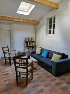 a living room with a blue couch and a table at Maison proche rivière - 6 à 8 personnes in Chambonas