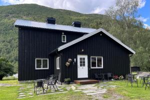 a black house with chairs in front of it at Nørdre-Repp in Boverdalen