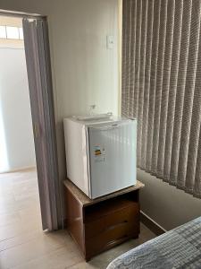 a small refrigerator sitting in a room next to a bed at Vilage Bed & Breakfast in Volta Redonda