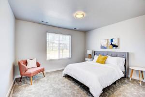 a bedroom with a bed and a chair and a window at BRAND NEW 4-BDRM HOME Farmhouse at Grand Rapids in Meridian