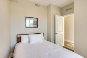 um quarto com uma cama com lençóis brancos em Modern Townhome with Rooftop Hot Tub and Mtn View em Denver