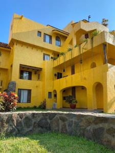 ein gelbes Gebäude mit einer Steinmauer davor in der Unterkunft Cómodo Depa en Club Santiago in Manzanillo