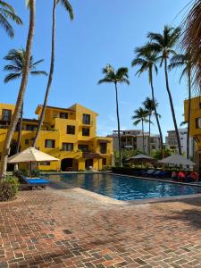 a swimming pool with palm trees and buildings at Cómodo Depa en Club Santiago in Manzanillo